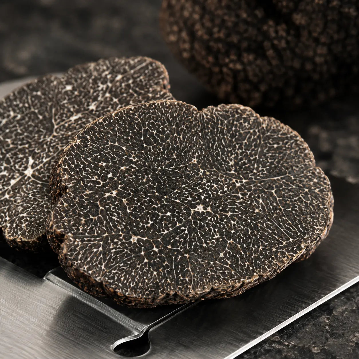 Cut Winter Black Truffle Tuber melanosporum showing dark marbled interior and premium texture